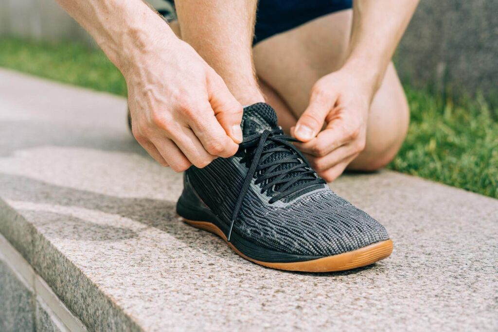 Sports man tying shoelace while running outdoors